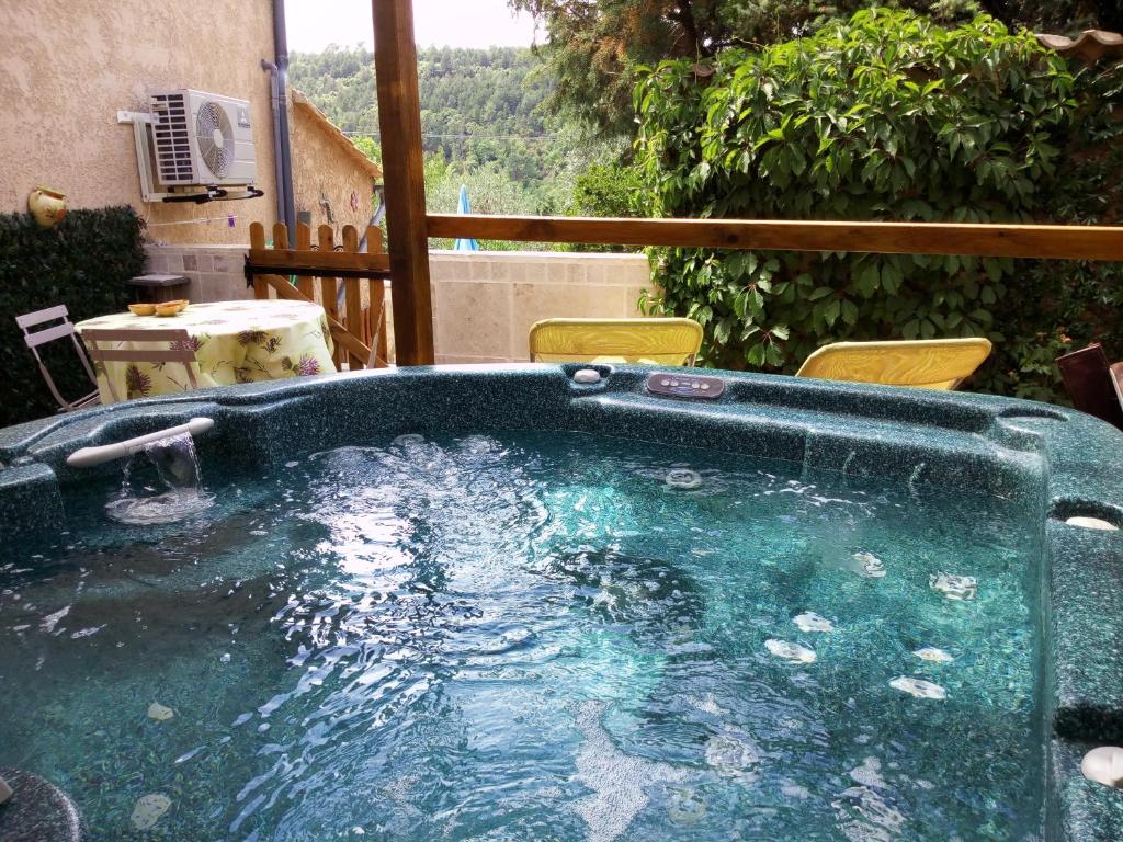 einen Whirlpool auf einer Terrasse mit Stühlen in der Unterkunft Les Lauriers Roses in Salavas