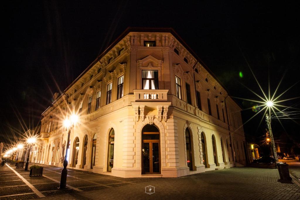 a large white building at night with lights at HOTEL CENTRAL CAREI in Carei