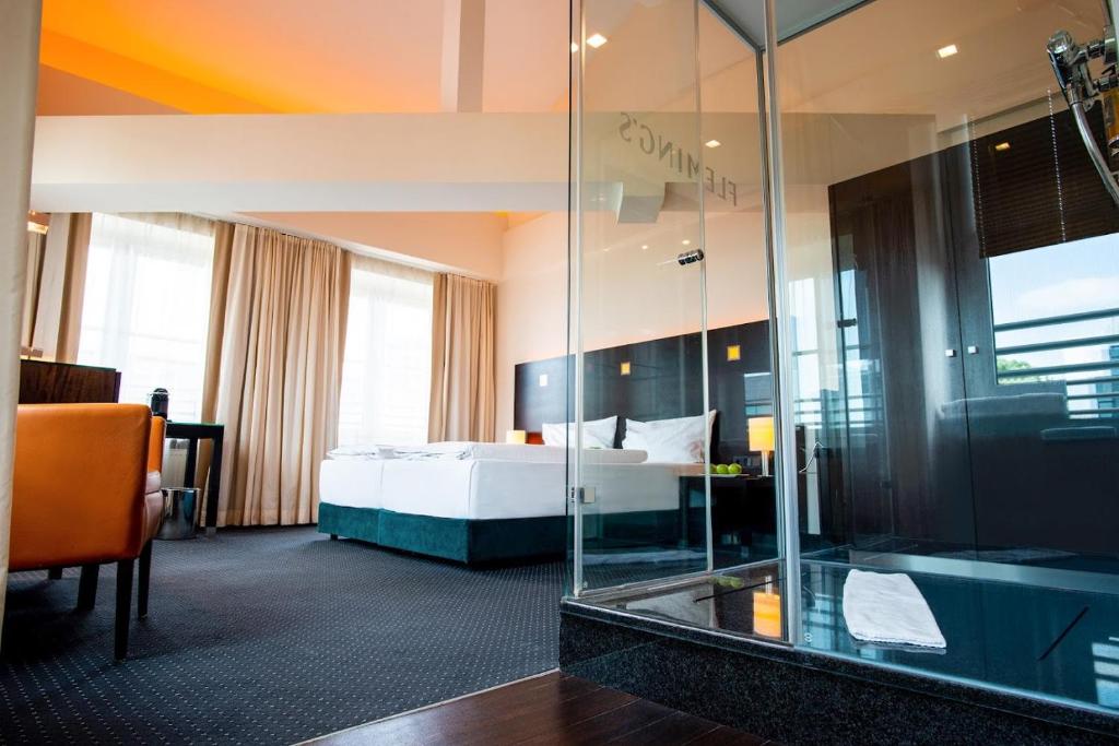 a hotel room with a bed and a glass wall at Flemings Hotel München-City in Munich