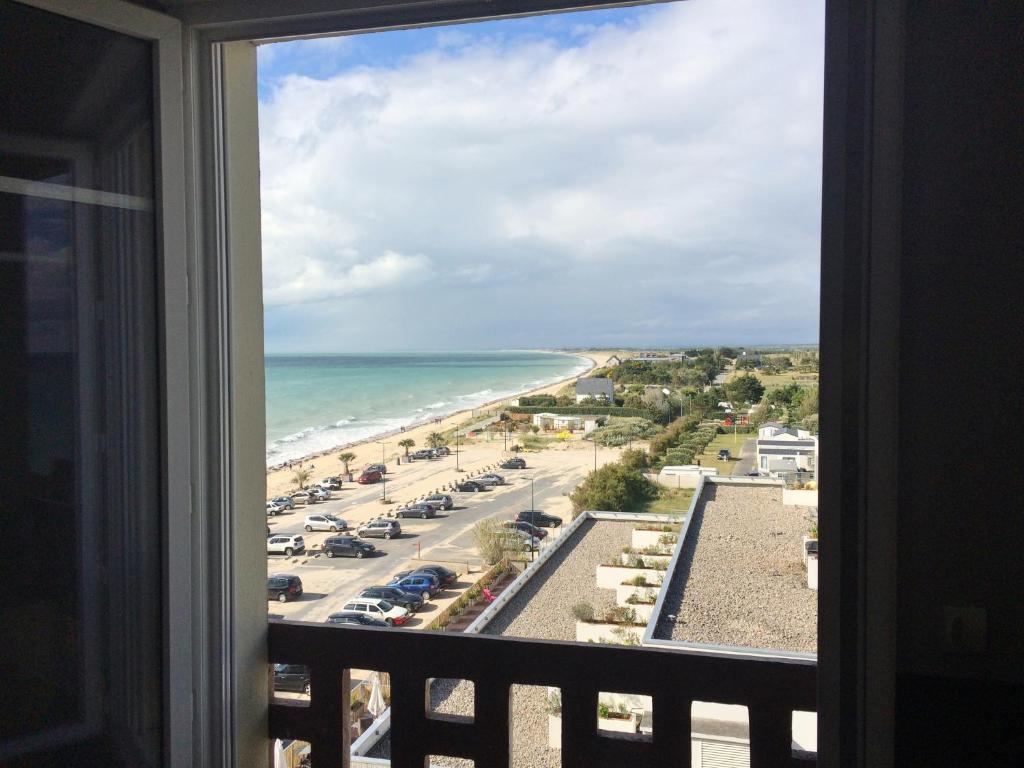 a view of a beach from a window at Studio~ Les pieds dans l'eau 2~ in Donville-les-Bains