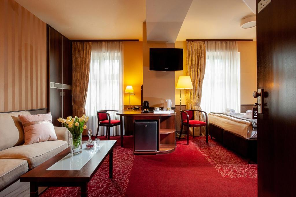 um quarto de hotel com um sofá e uma cama em Hotel Wielopole na Cracóvia