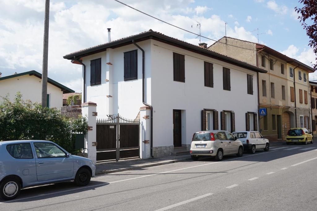 een wit huis met auto's geparkeerd aan de kant van een straat bij A Casa Mia in Romàns dʼIsonzo