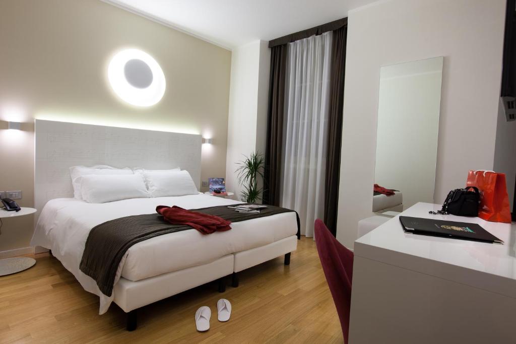 una camera con letto e scrivania e una camera di Hotel Coppe Trieste - Boutique Hotel a Trieste