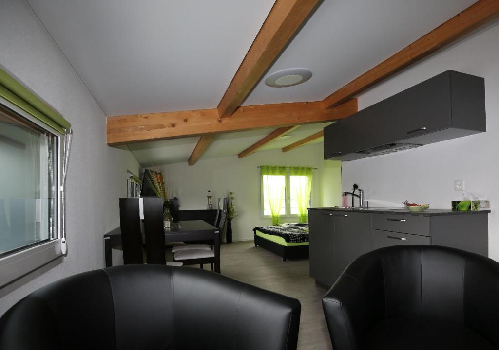 a living room with two black chairs and a kitchen at BeachIN - Sport, Events, Hotel, Restaurant, Bar in Ins