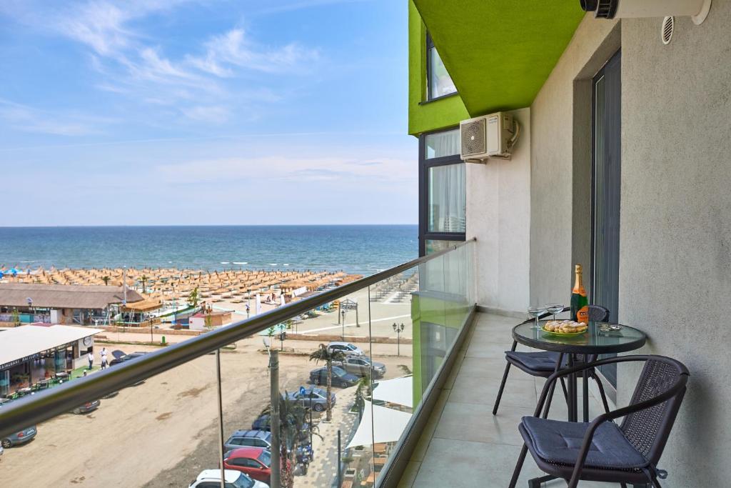 einen Balkon mit Tisch und Stühlen sowie Strand in der Unterkunft Green Apartment Spa n Pool Beach Resort in Mamaia Nord – Năvodari