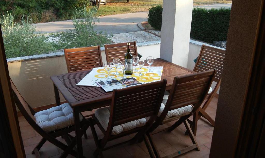 een houten tafel met stoelen en een fles wijn bij Delfin in Novigrad Istria