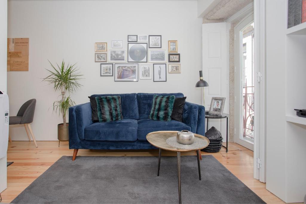 een woonkamer met een blauwe bank en een tafel bij Liiiving in Porto - Cozy & Chic Downtown in Porto