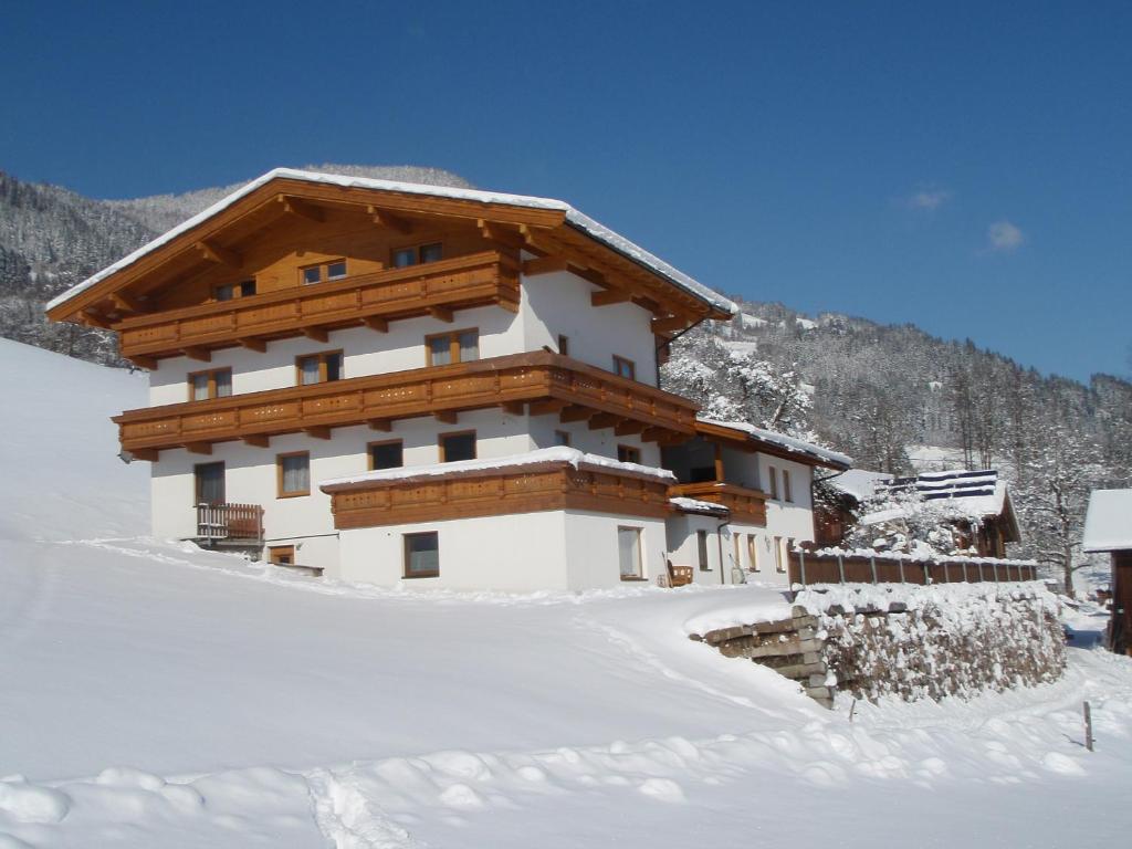 un edificio en la nieve frente a una montaña en Obermooshof, en Fügenberg