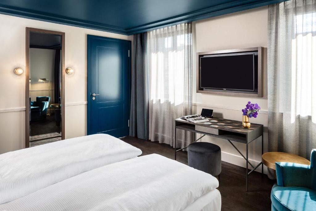 a hotel room with two beds and a desk with a tv at Hotel AMO by AMANO Friedrichstraße in Berlin