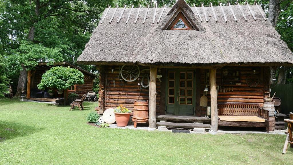 a small cabin with a thatched roof on the grass at Veski Aida Holiday Home in Käina