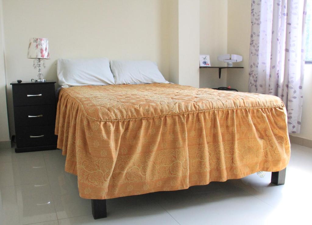 Un dormitorio con una cama con una manta naranja. en Hostal du Parc, en Trujillo