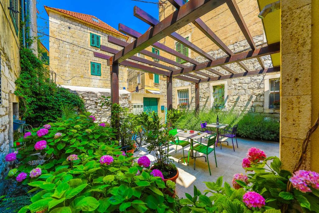 une terrasse avec des fleurs et une pergola en bois dans l'établissement Apartments Veig, à Split