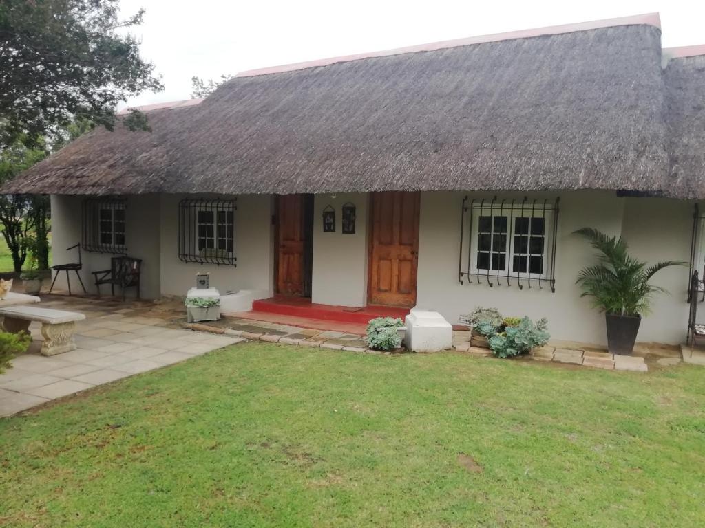 a small white house with a thatched roof at Erin Guesthouse and B&B in Bergville