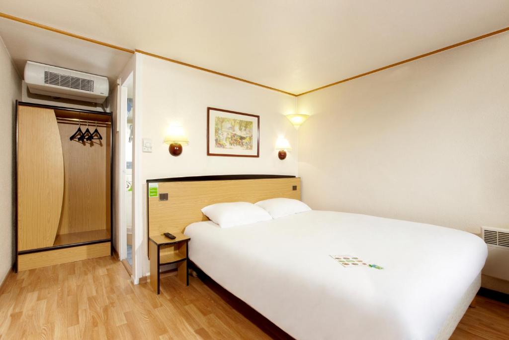 ein Schlafzimmer mit einem großen weißen Bett in einem Zimmer in der Unterkunft Campanile Nevers Nord - Varennes-Vauzelles in Varennes-Vauzelles