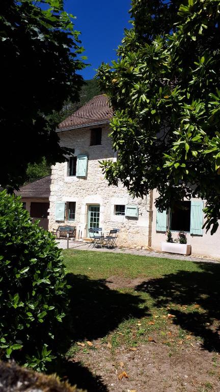 une grande maison en pierre avec un arbre en face de celle-ci dans l'établissement Gîte entre Vignes et Montagne, à Lhuis