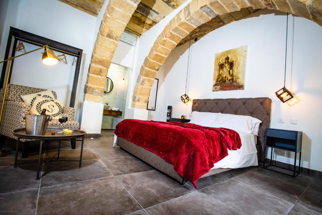 1 dormitorio con 1 cama grande y 1 mesa en Pjazza Suites Boutique Hotel by CX Collection, en Siġġiewi
