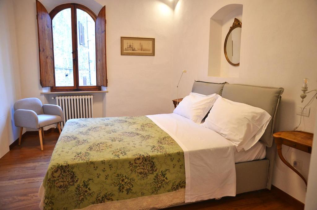 una camera con un letto e una sedia e una finestra di S.M. VICOLO DELL'ORO a San Gimignano