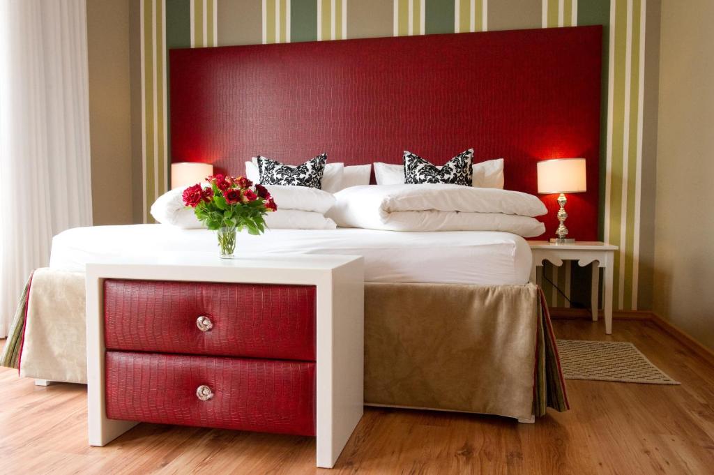 a bedroom with a large bed with a red headboard at Namib Guesthouse in Swakopmund