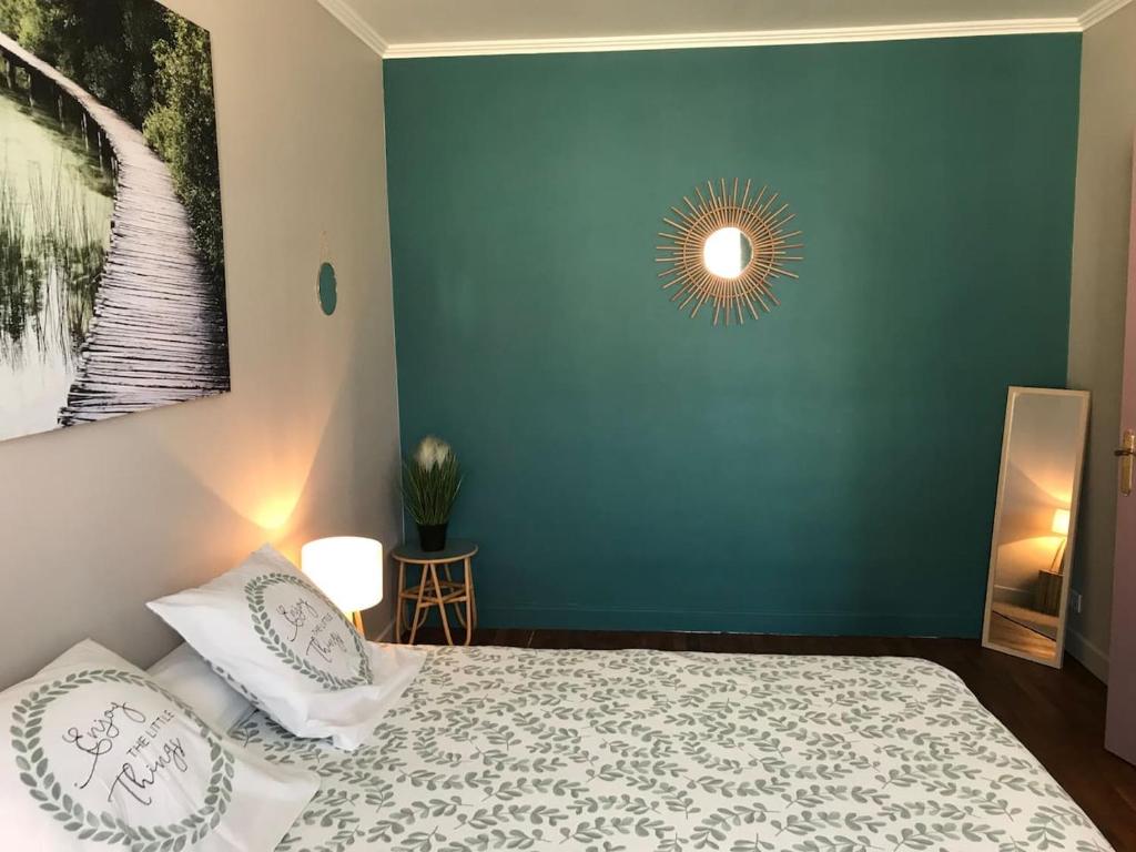 ein Schlafzimmer mit einer grünen Wand und einem Bett mit Kissen in der Unterkunft appartement de charme en plein coeur du centre ville de Compiègne in Compiègne