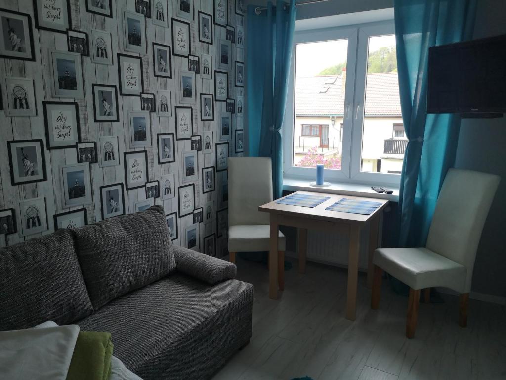 een woonkamer met een bank, een tafel en een raam bij Apartamenty Hejszowina in Kudowa-Zdrój