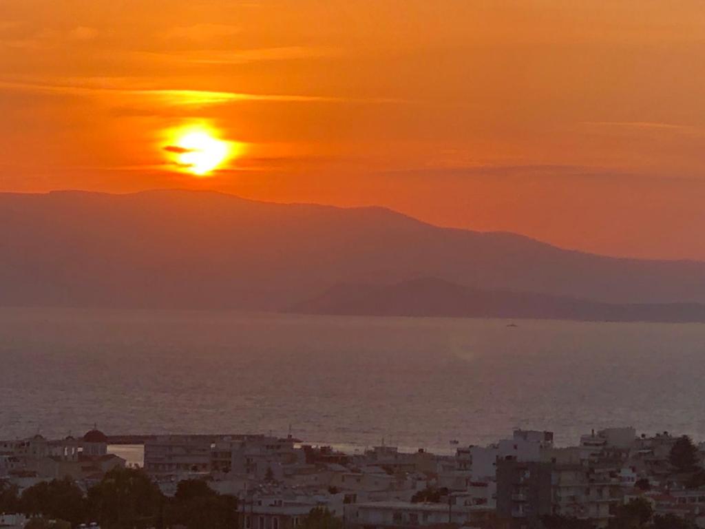 a sunset over a city and the ocean with mountains at xanthippi in Varvásion
