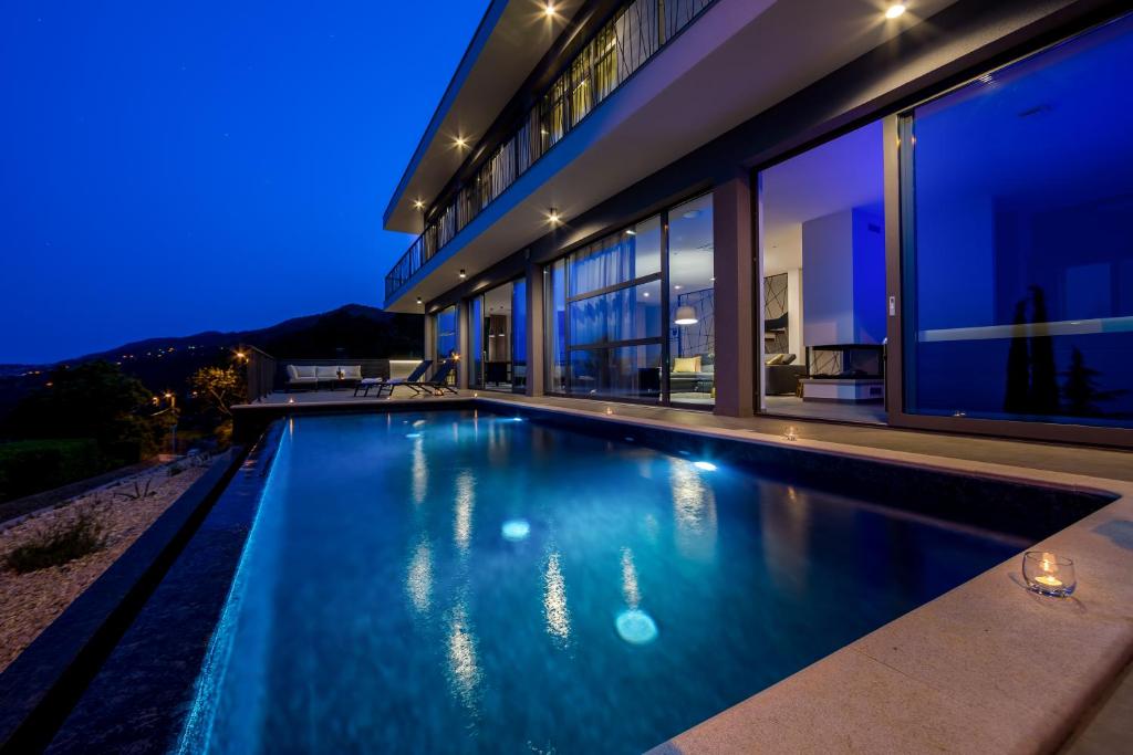 a swimming pool in front of a house at night at Villa The View in Poljane
