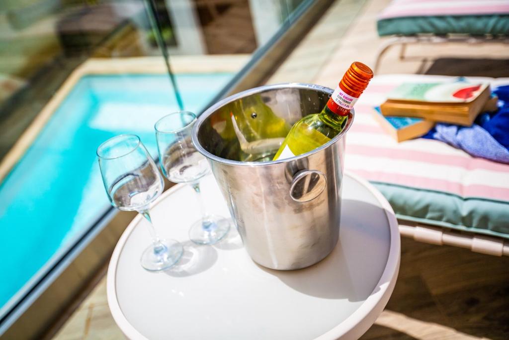 a bucket of wine and glasses on a table next to a pool at Pjazza Suites Boutique Hotel by CX Collection in Siġġiewi