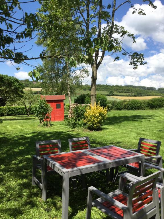 een tafel en stoelen in een veld met een rode schuur bij Gîtes les amis de l Authie in Maintenay