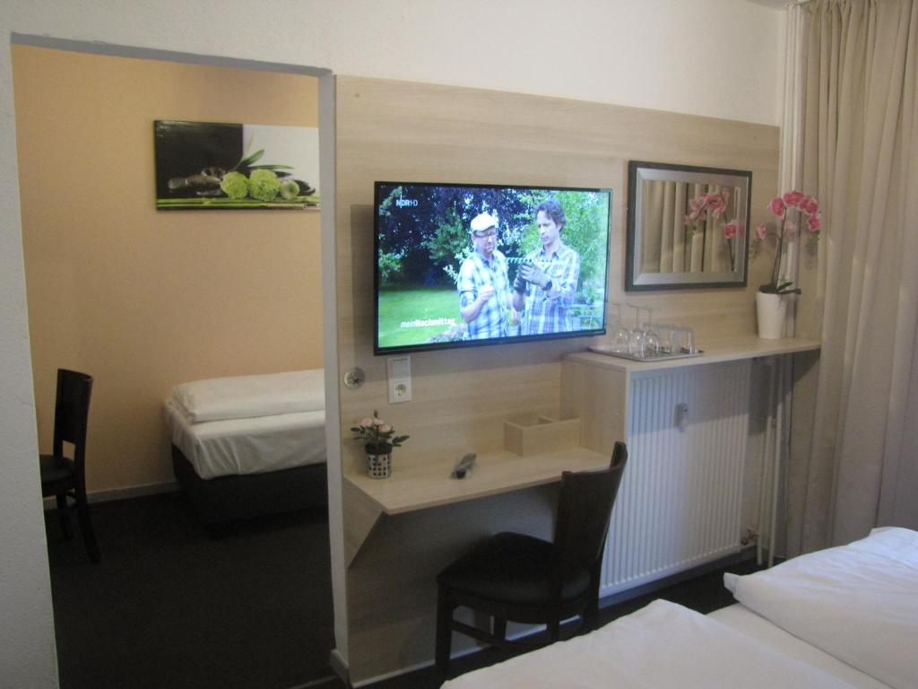 a hotel room with a tv and a desk in a room at Milano Hotel in Hamburg