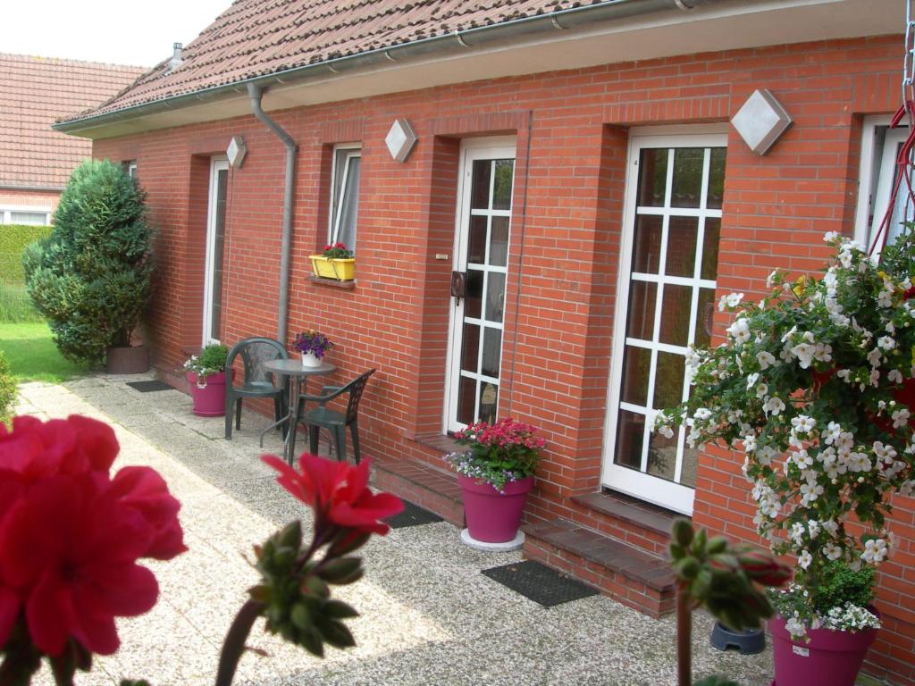 ein rotes Backsteinhaus mit einer Terrasse mit Blumen in der Unterkunft Appartements Krüger in Hage