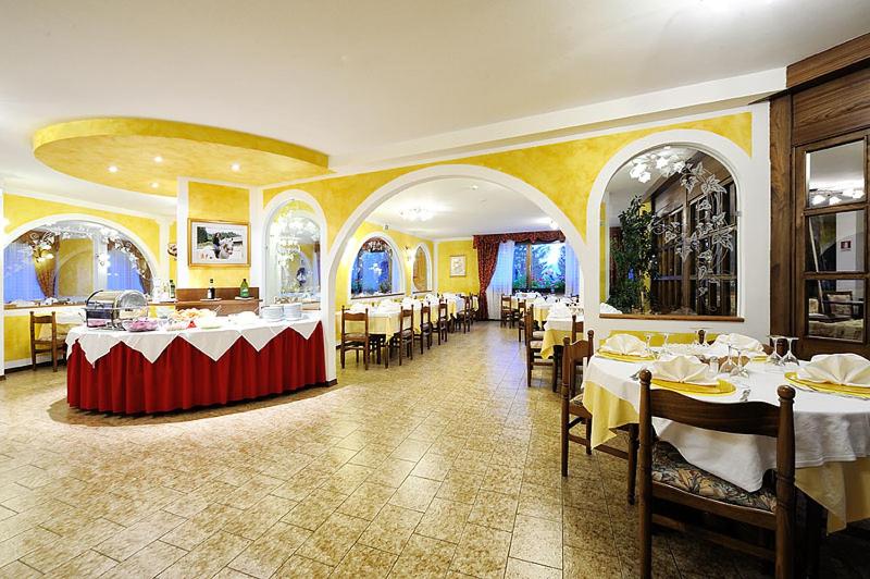 a restaurant with tables and chairs in a room at Hotel Europa in San Martino di Castrozza
