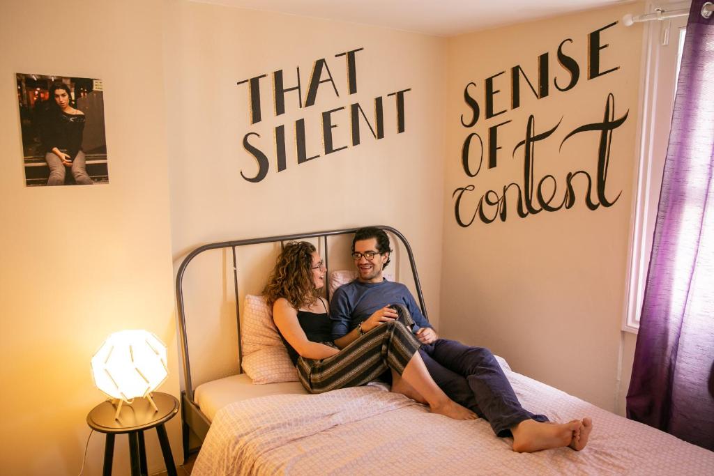 a man and a woman sitting on a bed at Onefam Notting Hill in London