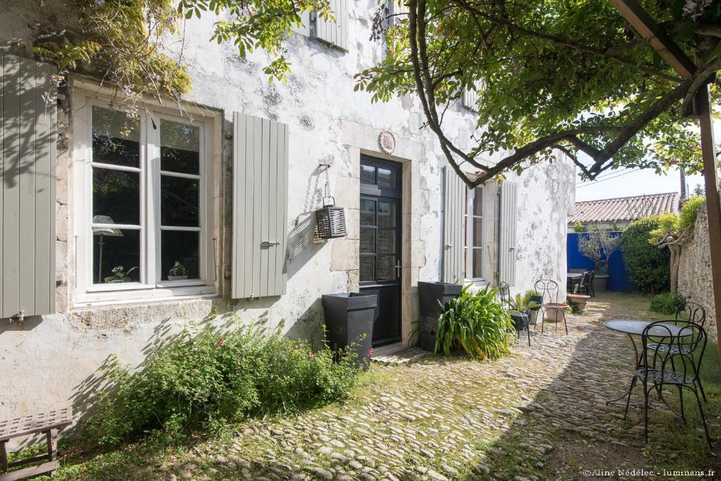 ein weißes Gebäude mit einem Fenster, einem Tisch und Stühlen in der Unterkunft Le Clos du Vieux Porche in La Couarde-sur-Mer
