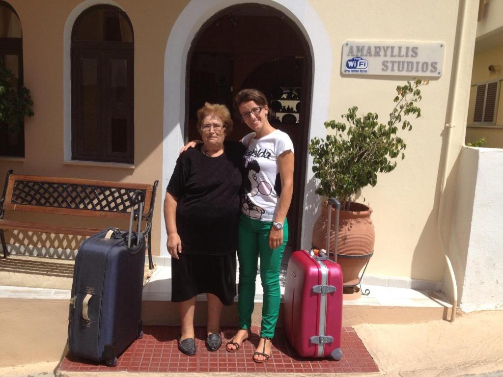 two women standing in front of a building with luggage at Amaryllis Hotel in Karpathos