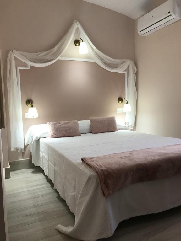 a bedroom with a large white bed with two lights at Emperador Augusto in Mérida