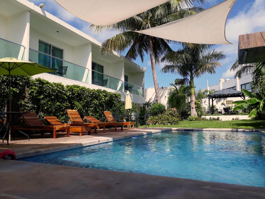 a swimming pool next to a building with chairs and an umbrella at Hotel Villa Escondida Campeche in Campeche