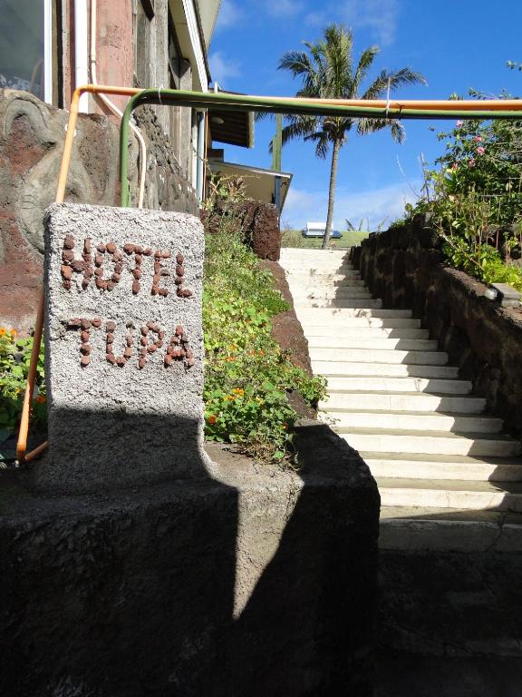 a sign on the side of a building with stairs at Tupa Hotel in Hanga Roa