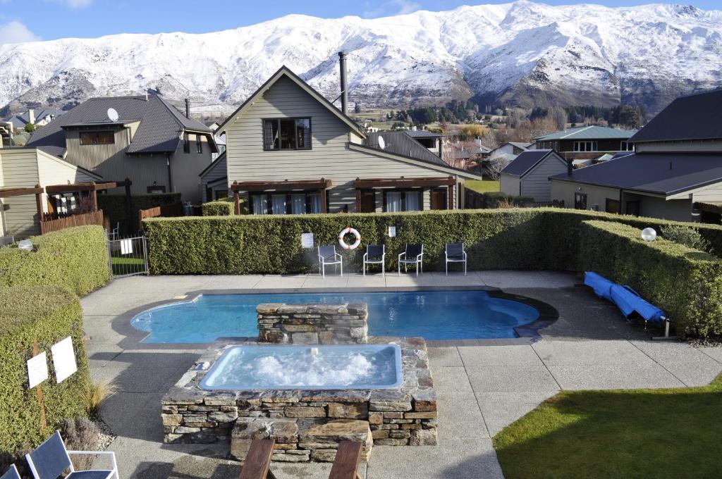 a swimming pool in a yard with mountains in the background at Wanaka Luxury Apartments in Wanaka