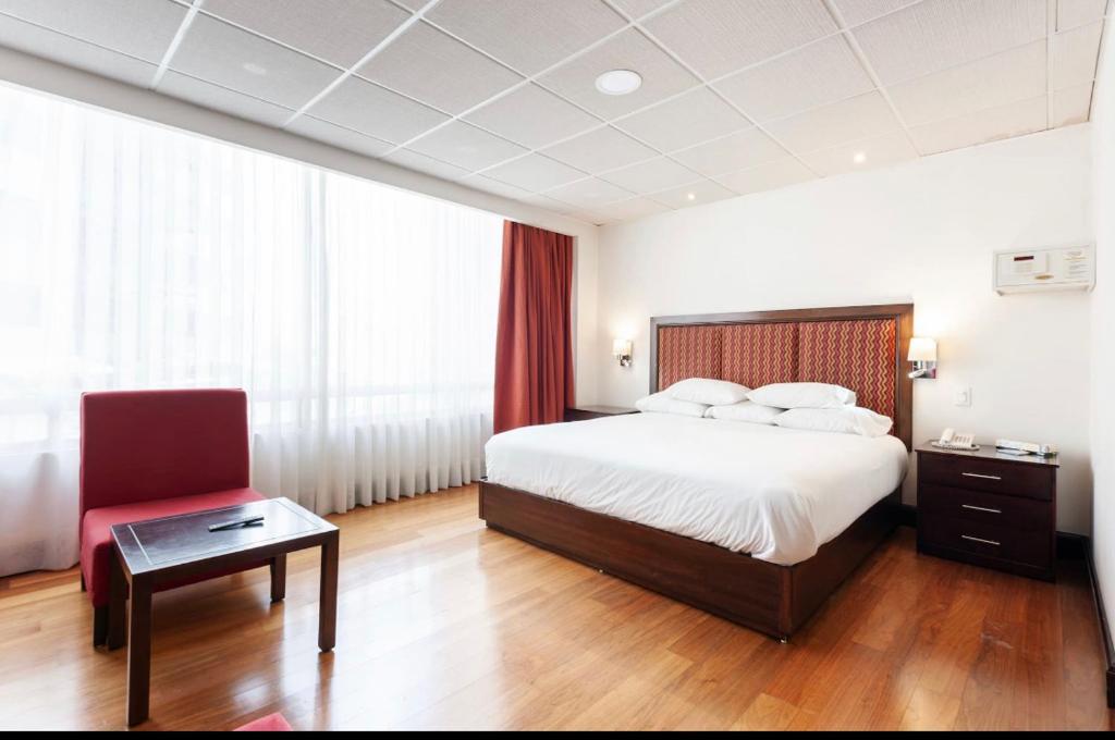 une chambre d'hôtel avec un lit et un fauteuil rouge dans l'établissement Suites Melchor Ocampo 445, à Mexico