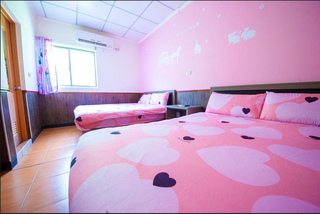 a pink room with a bed and a couch at Hai Yin in Green Island