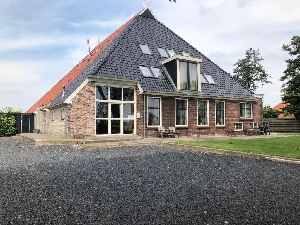 une maison en briques avec un toit en gambrel dans l'établissement Bed & Breakfast Ytsma State, à Follega