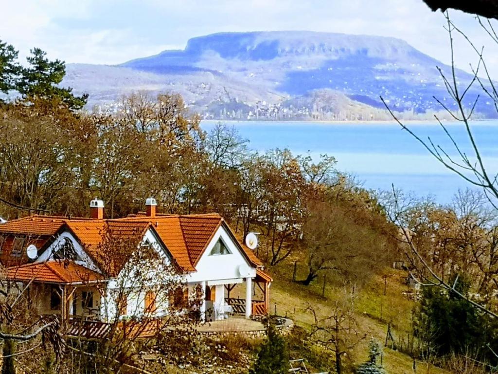 uma casa com um telhado laranja no topo de uma colina em Ezüsthíd Apartman em Balatongyörök