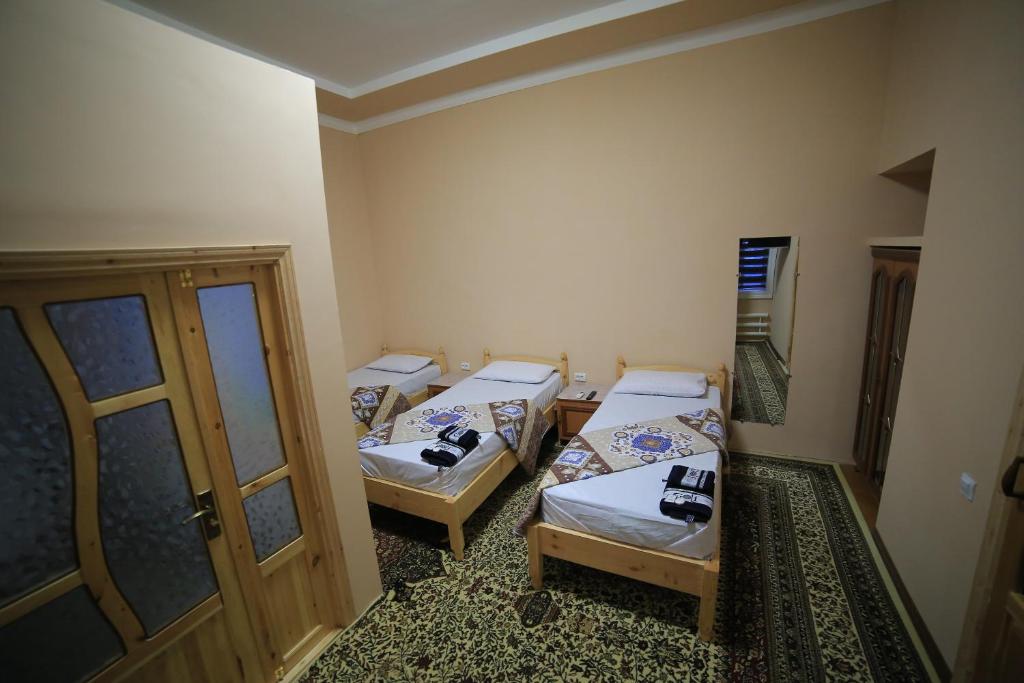 a room with three beds in it with a door at PARVIZ GUEST HOUSE in Bukhara