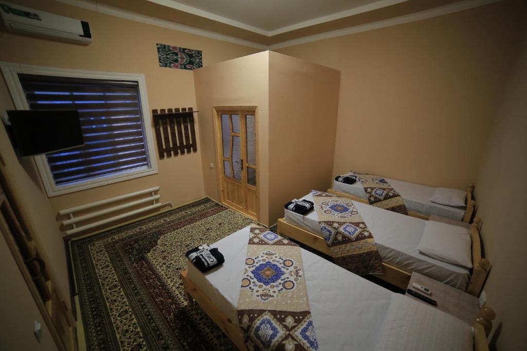 1 dormitorio con 2 camas, TV y ventana en PARVIZ GUEST HOUSE, en Bukhara