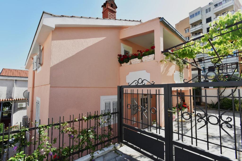 różowy dom z czarnym żelaznym płotem w obiekcie Apartments Marko w mieście Herceg Novi