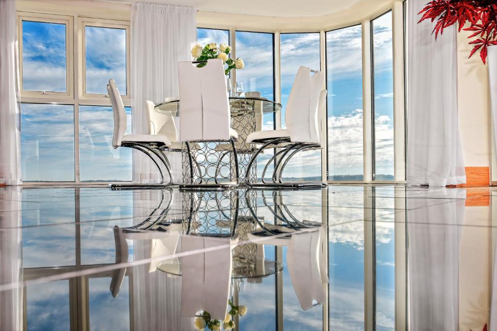 comedor con mesa de cristal y sillas blancas en Just Stay Wales - Meridian Quay Penthouses en Swansea