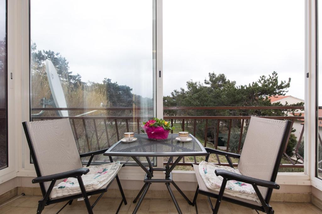 einen Tisch und zwei Stühle auf einem Balkon mit Fenster in der Unterkunft Apartment Calista in Rabac