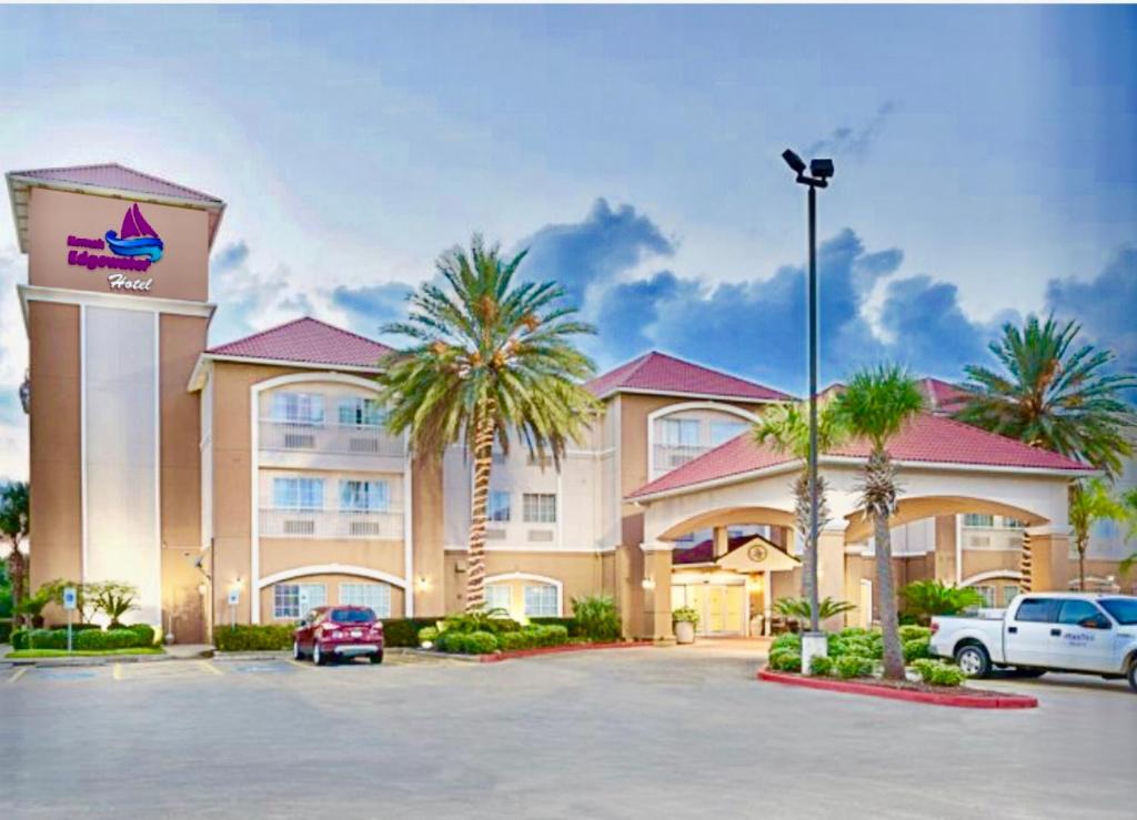 a hotel with palm trees in a parking lot at Kemah Edgewater Hotel in Seabrook