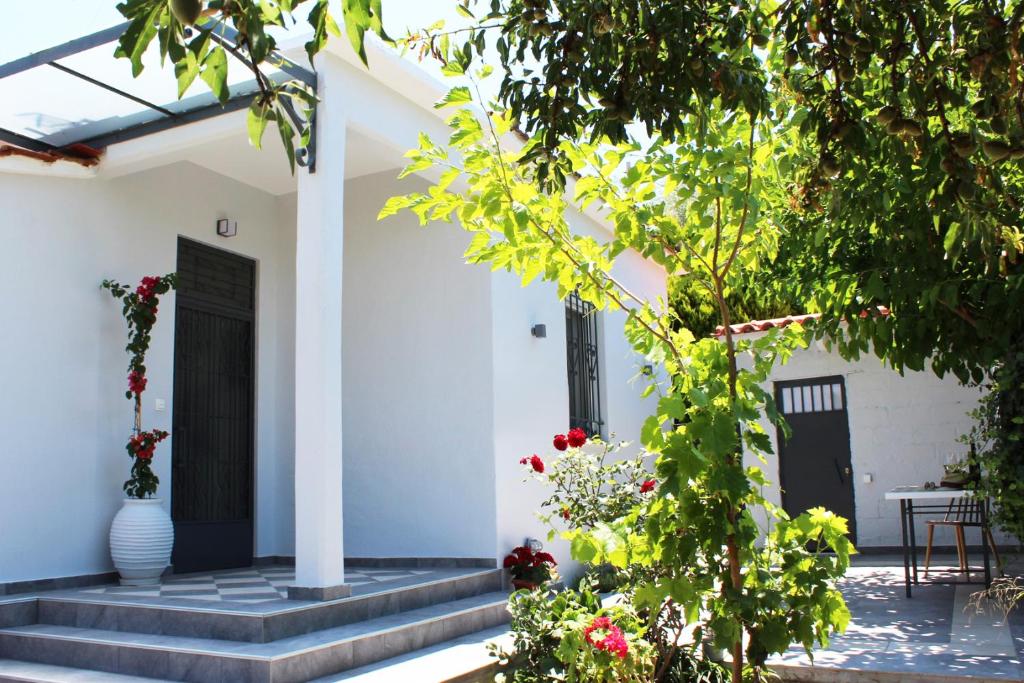 a white house with a black door and some flowers at ORANGE GARDEN in Aigio