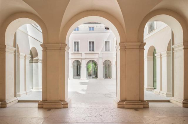 an empty arcade with columns and a white building at PALAZZO BECCAGUTTI CAVRIANI - Gallery Suite e Frescoes Suite in Mantova